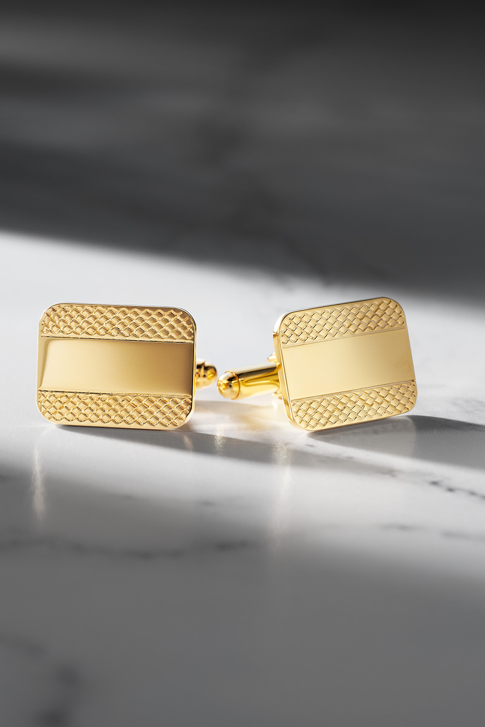 Gold ornate cufflinks on a marble table.