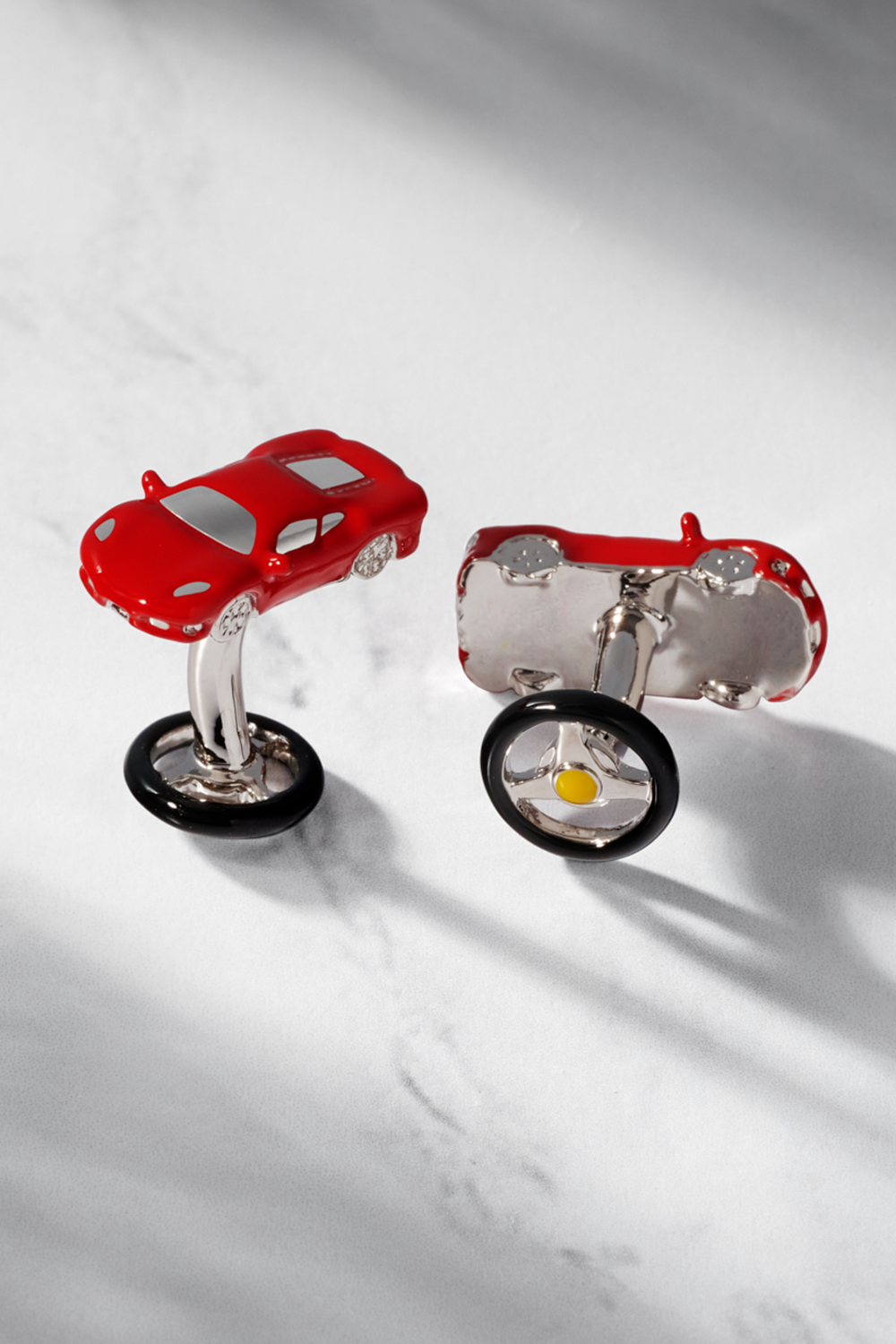 Red sports car cufflinks on a marble surface.