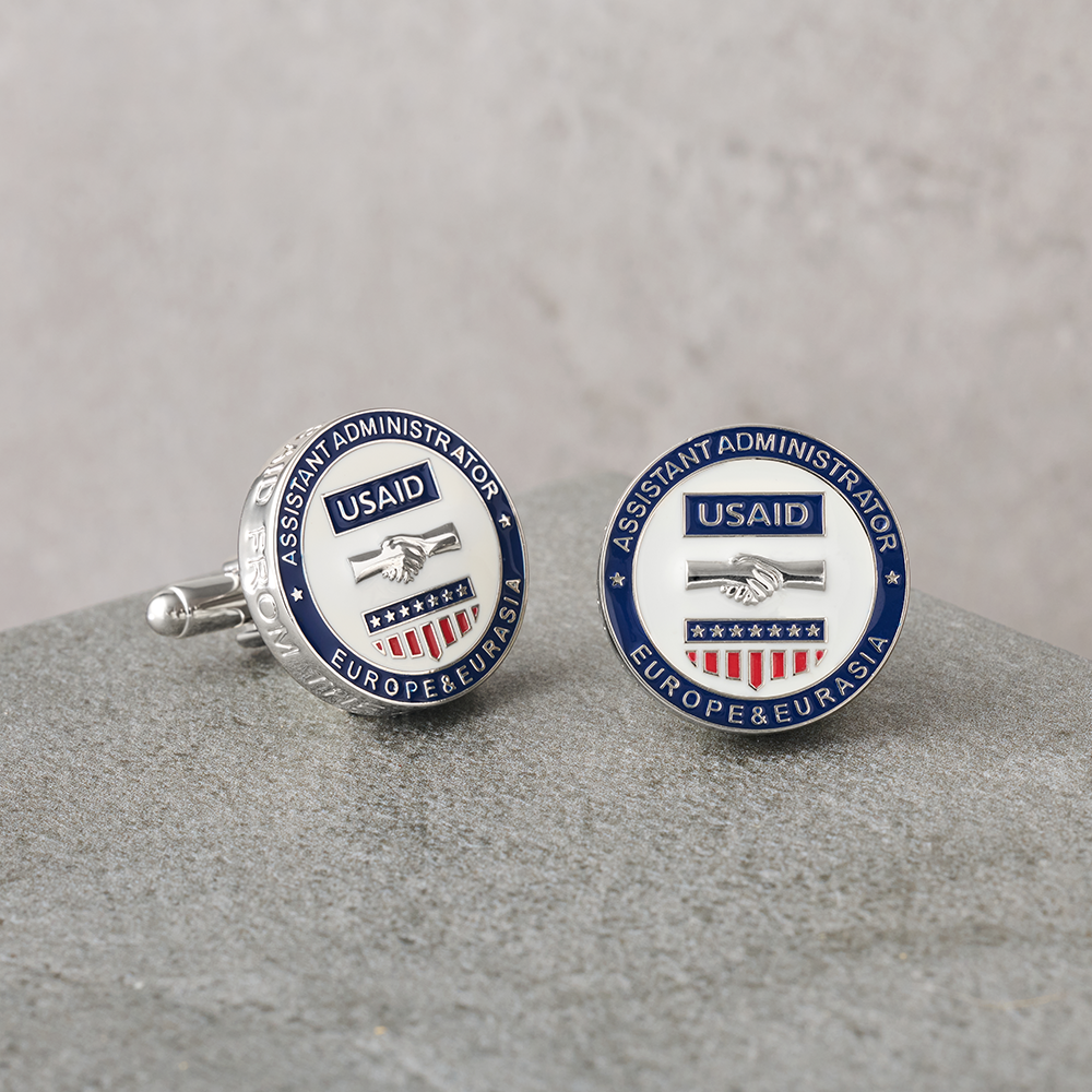 Custom USAID Cufflinks on a gray table and gray background.