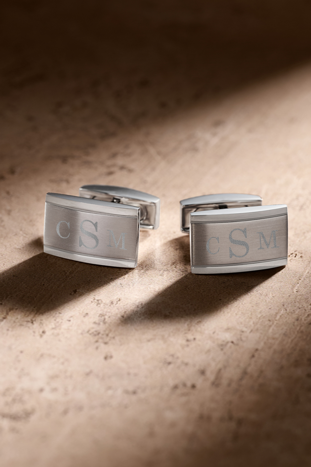 Silver cufflinks on a tan background.