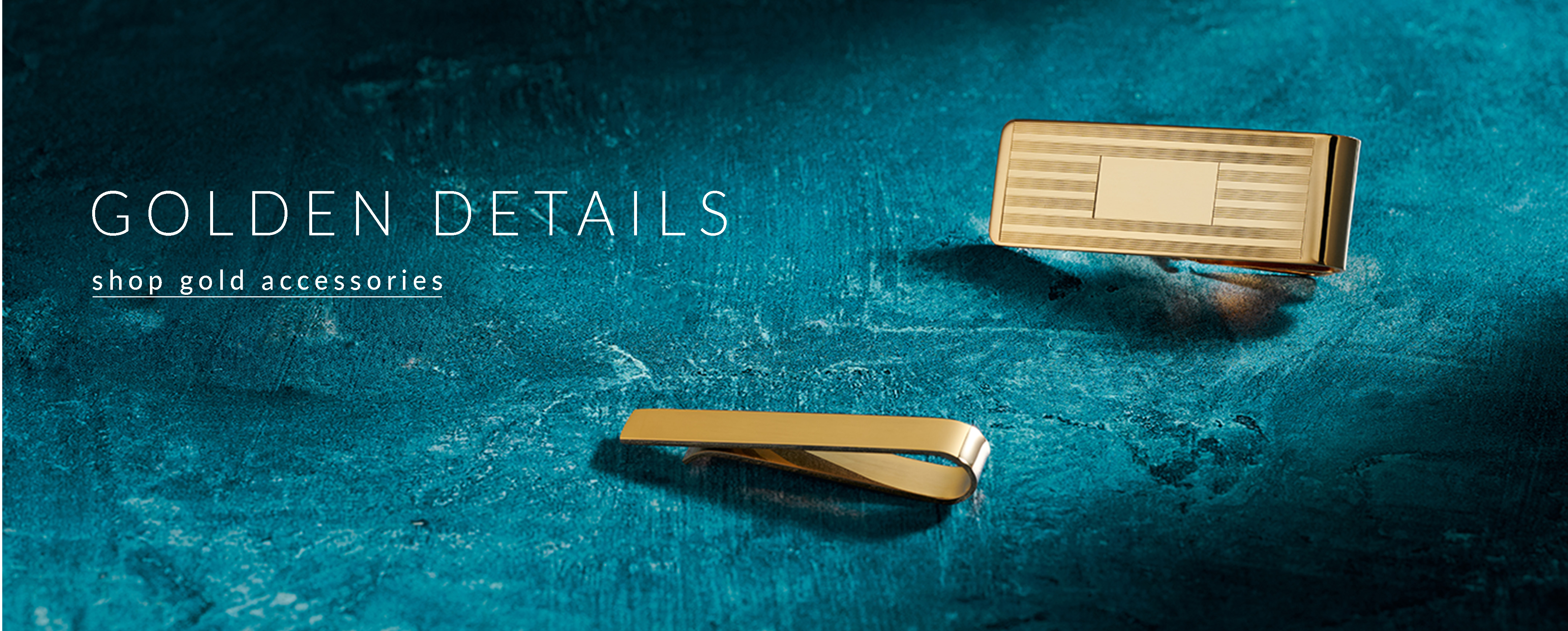 Shop Gold Accessories. Gold money clip and gold tie bar on a blue-green background.