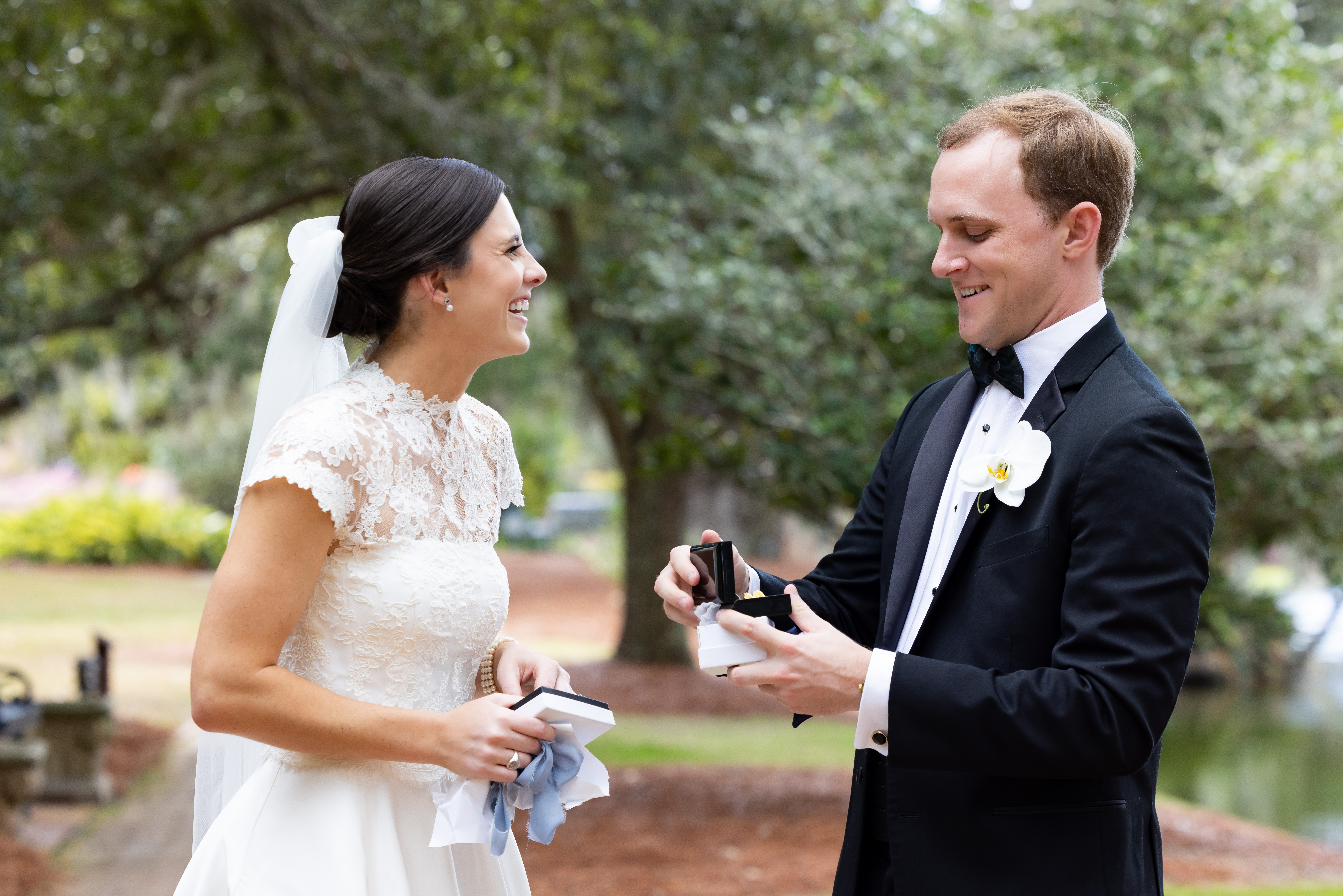 A bride giving her groom a gift of custom cufflinks on the day of their wedding, outside.